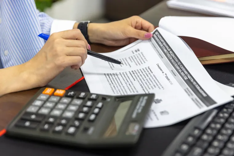 Un profesional de finanzas revisando documentos impresos con una calculadora en un escritorio